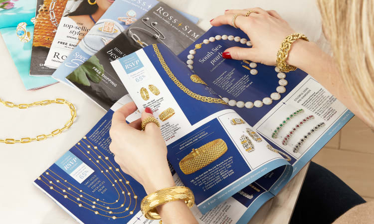 Woman wearing gold jewelry looking at Ross-Simons catalogs.